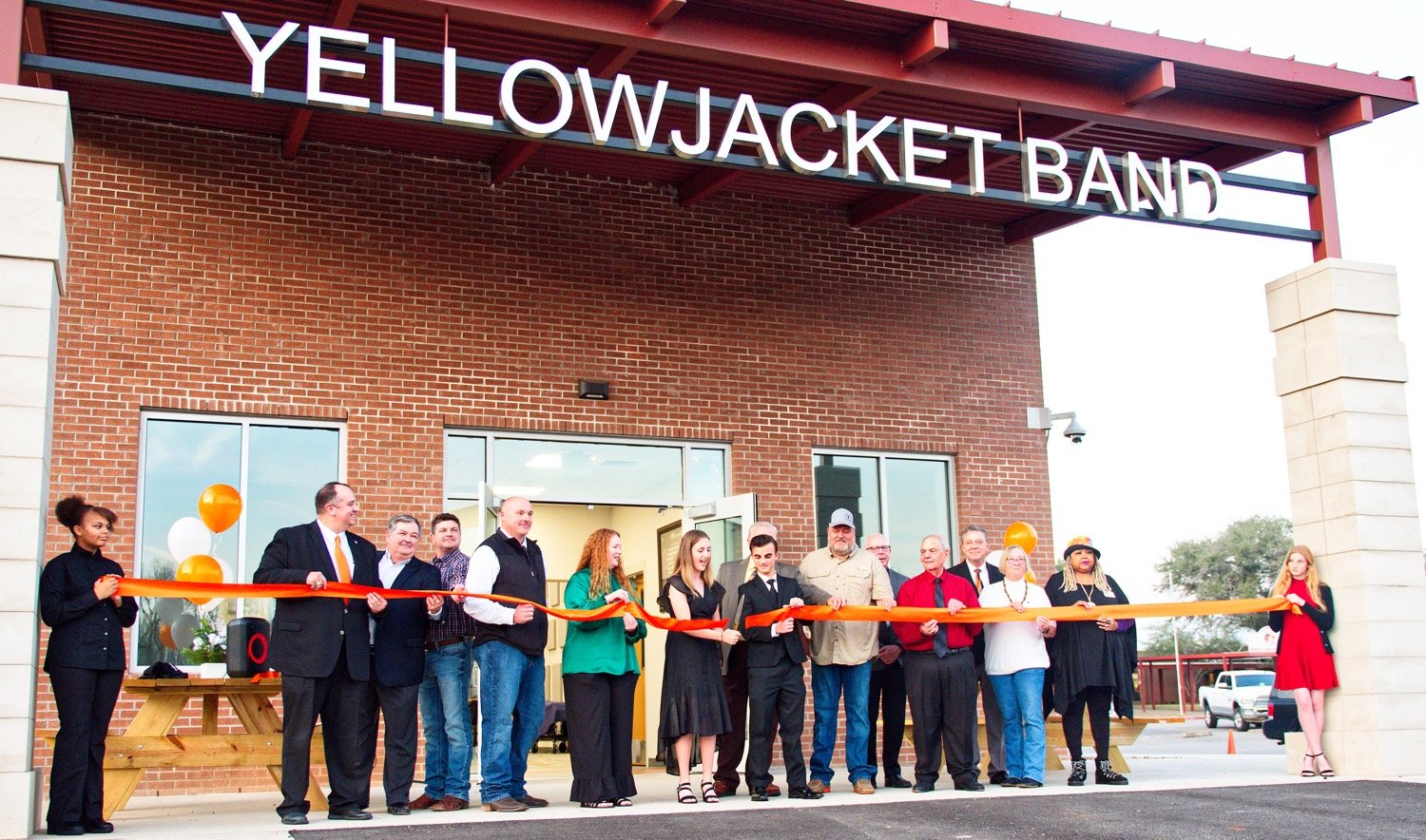 Taking part were, from left, Kaleece Palmer, Superintendent Cody Mize, architect Perry Thompson, construction manager Wes McClure with Sherrill Construction, school board members Jay McGough and Jill Quiambao, cutting the ribbon drum majors Maddie Tucker and Cameron Bussell (in front of board member Glen Dossett), board member Robbie Ballard, business manager William Bjork, board president John Abbott, high school Principal Mike Sorenson, Mayor Jayne Lankford, council member Cassandra Sampson and Tori Kinder. [see more of the celebration]